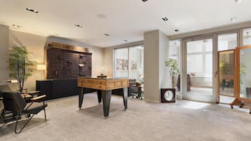 Un espace de bureau moderne comprenant un bureau, des chaises, une bibliothèque et une grande fenêtre.