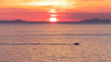Un atardecer sobre un mar tranquilo con un barco al frente.