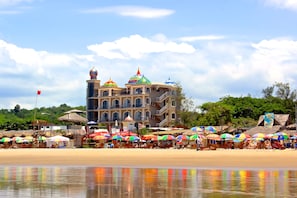 A beachside hotel with multiple colorful umbrellas, a large building with domed roofs, and a clear sky. - Dharma Beach Hotel (Manglaralto)