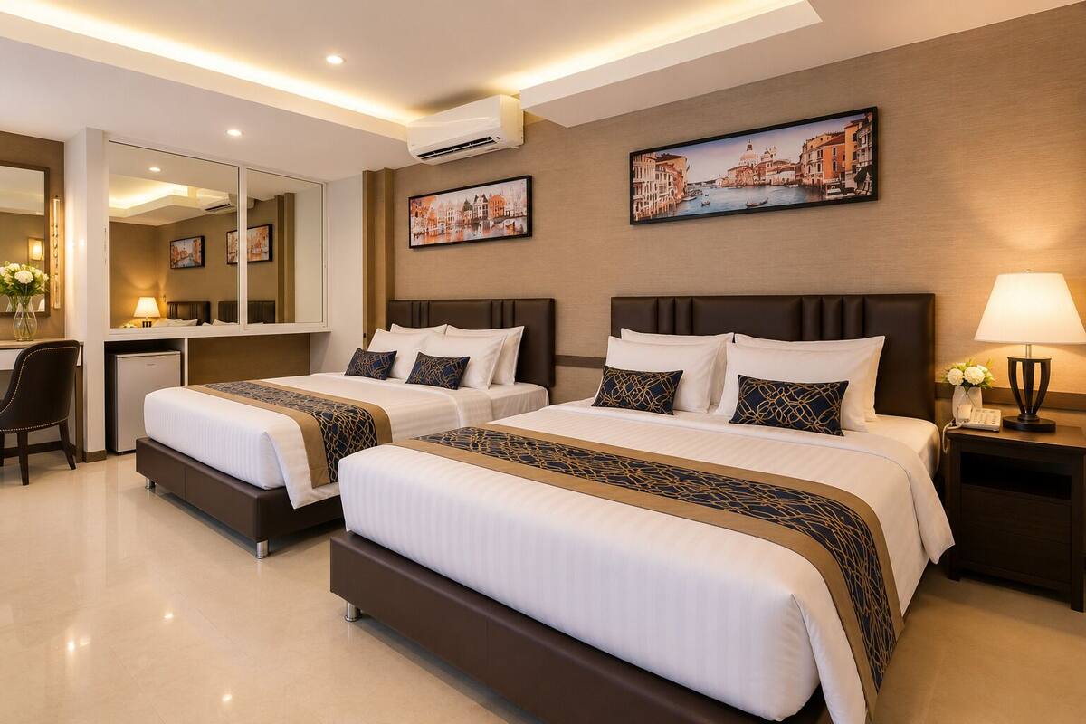 Ein Hotelzimmer mit zwei Betten, einem Schreibtisch, einem Stuhl, einem Spiegel und Kunstwerken an den Wänden.