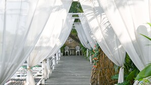 Een houten brug met witte leuningen en witte draperieën.