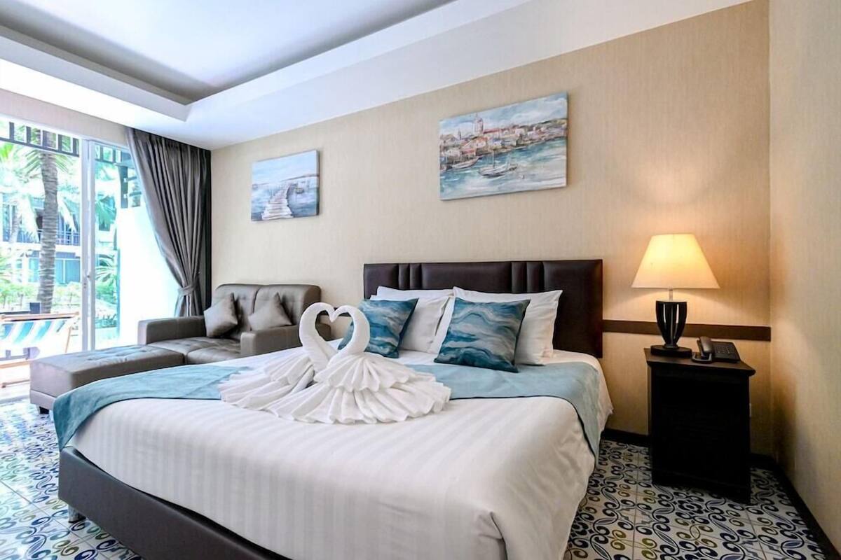 Ein Hotelzimmer mit Bett, einer Couch, einem Nachttisch und Blick ins Freie.