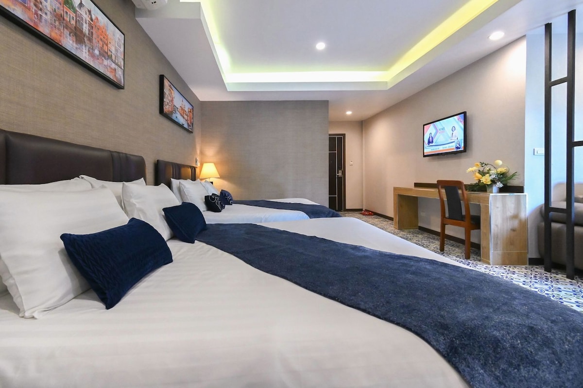 Ein Hotelzimmer mit zwei Betten, einem Schreibtisch und einem Fernseher.