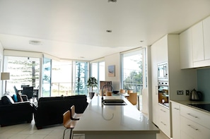 Una cocina moderna con una isla central, ventanas amplias y una zona de comedor con sofá y sillas.