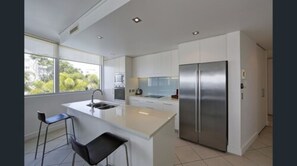 Una cocina moderna con una isla central, electrodomésticos de acero inoxidable y un amplio ventanal que proporciona luz natural.