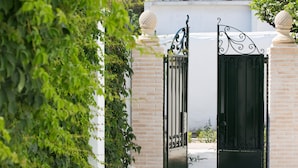 A gated entrance with a brick wall and a decorative metal gate. - Kouneni Apartments (Mykonos)