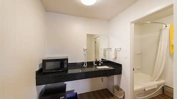 A modern bathroom with a black countertop, a white sink, a mirror, a shower, and a toilet.
