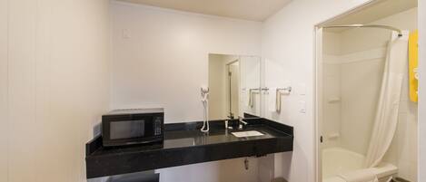 A modern bathroom with a black countertop, a white sink, a mirror, a shower, and a toilet.