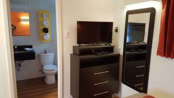 A bedroom with a bed, a dresser, a television, and a mirror.
