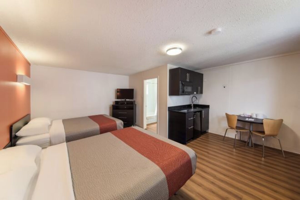 Ein Hotelzimmer mit zwei Betten, einer Küchenzeile und einem Essbereich.