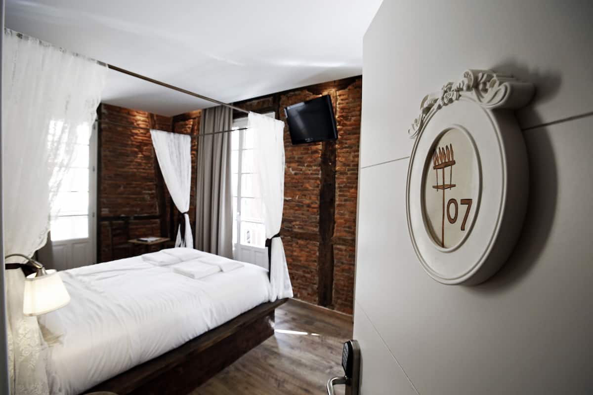 A bedroom with a bed, a TV mounted on the wall, and a number 07 sign.