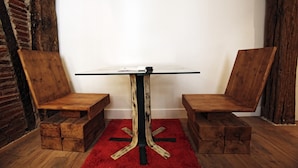 A table with a glass top and wooden legs, flanked by two wooden chairs with a red rug underneath. - Pensión Basque Boutique (Bilbao)