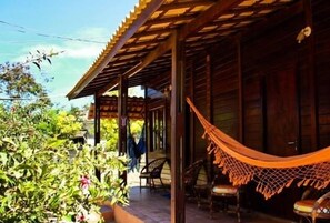 Ein Holzhaus mit überdachter Veranda, Außenmöbeln und einer Hängematte.