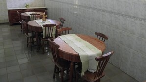 A dining area with wooden tables and chairs, a tiled floor, and a window with a view. - Pousada Ares de Noronha (Fernando de Noronha)