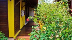A wooden building with a yellow exterior, a covered walkway, and lush greenery. - Pousada Ares de Noronha (Fernando de Noronha)