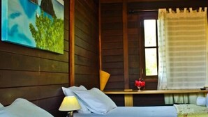A room with two beds, a window with curtains, a painting on the wall, and a small table with a lamp. - Pousada Ares de Noronha (Fernando de Noronha)
