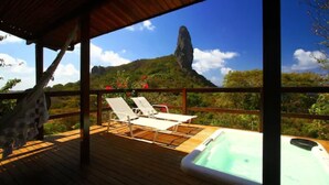 A wooden deck with lounge chairs and a hot tub, overlooking a mountainous landscape. - Pousada Zé Maria (Fernando de Noronha)