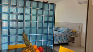 Une cuisine moderne avec un plan de travail noir, des chaises jaunes et un panier de fruits.