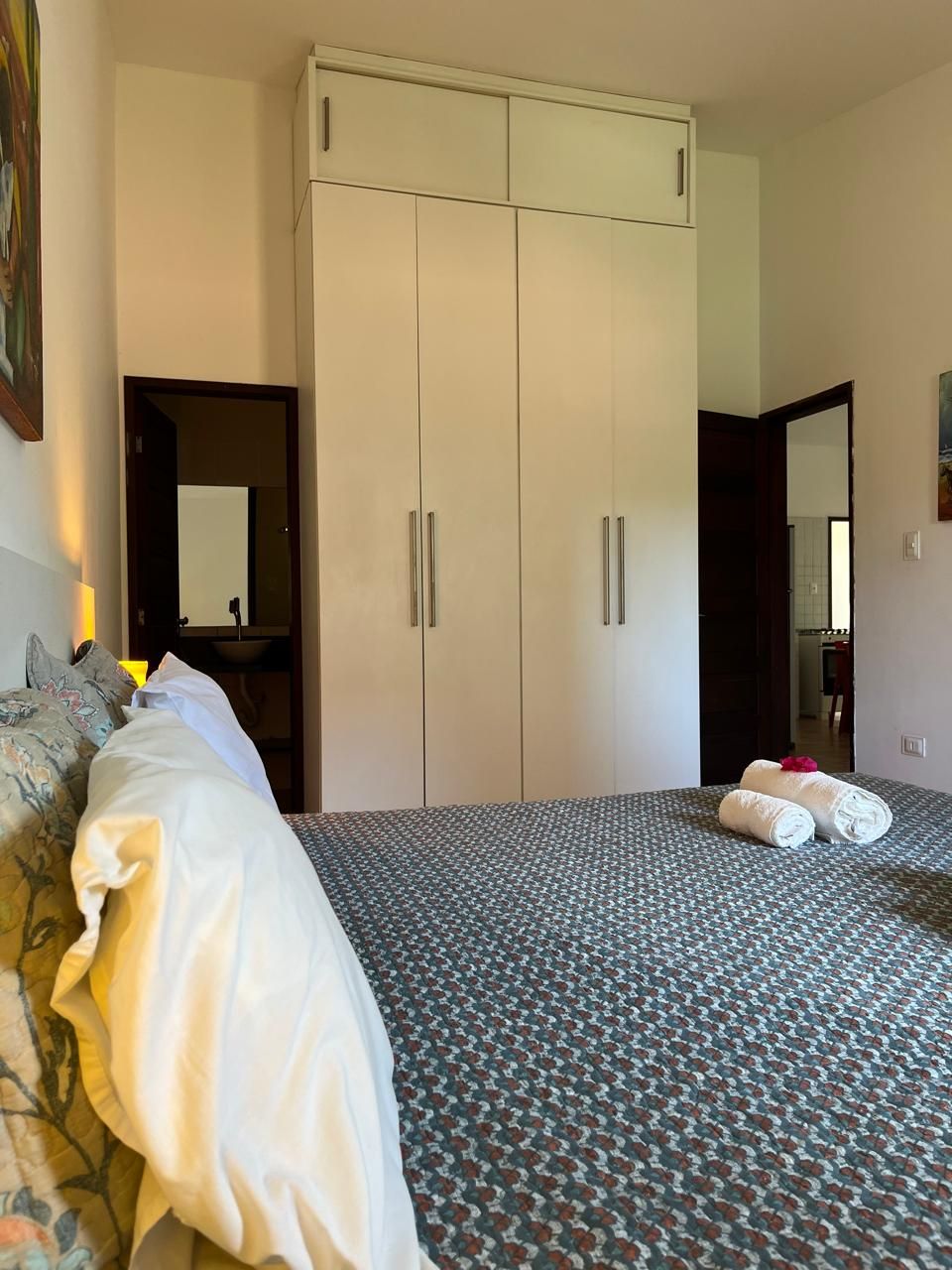 Una habitación de hotel con cama, armario, baño con espejo y lavabo.