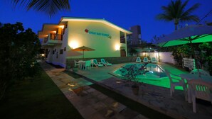 Un hôtel doté d’une piscine, d’un espace extérieur aménagé et d’une façade bien éclairée.