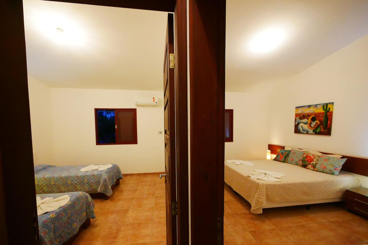 Habitación de hotel con dos camas, una ventana, un cuadro y una lámpara en el techo.