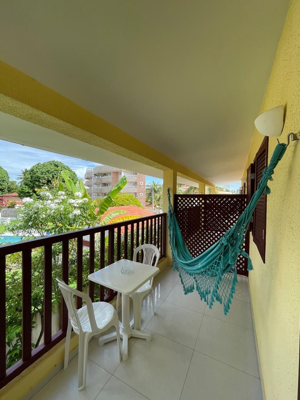 A balcony with a table and chairs, a hammock, and a view of the surrounding area.