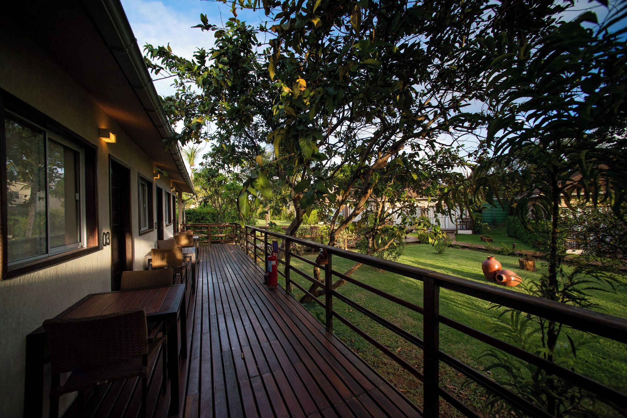 A wooden deck with outdoor seating, surrounded by lush greenery and a well-maintained lawn.