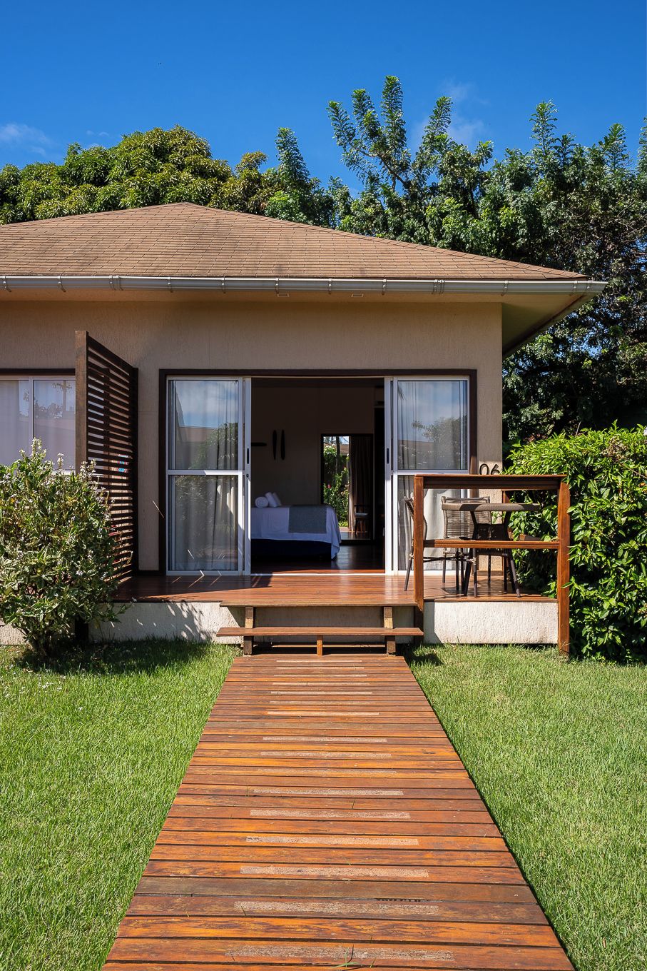 A modern house with a wooden deck leading to a glass door entrance.