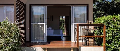 A modern house with a wooden deck leading to a glass door entrance.