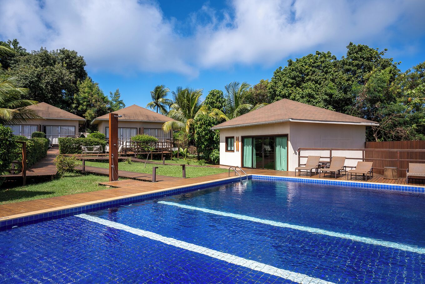 A pool area with a clear blue pool, wooden deck, and lounge chairs.