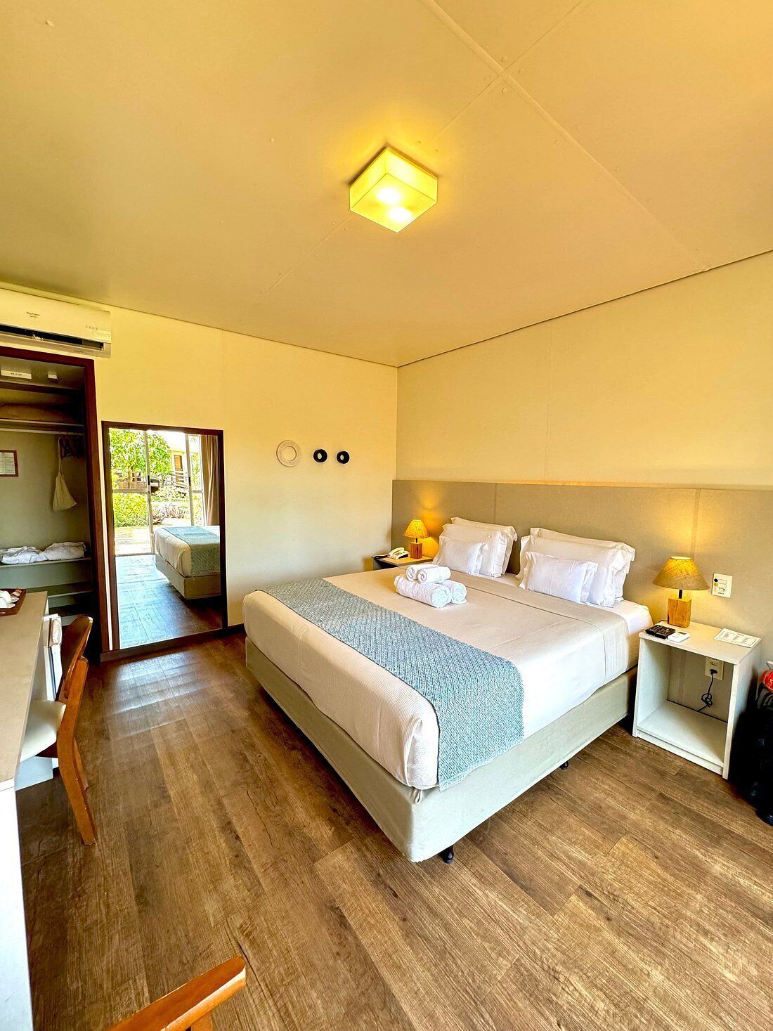 A hotel room with a large bed, bedside lamps, a desk, and a wardrobe.