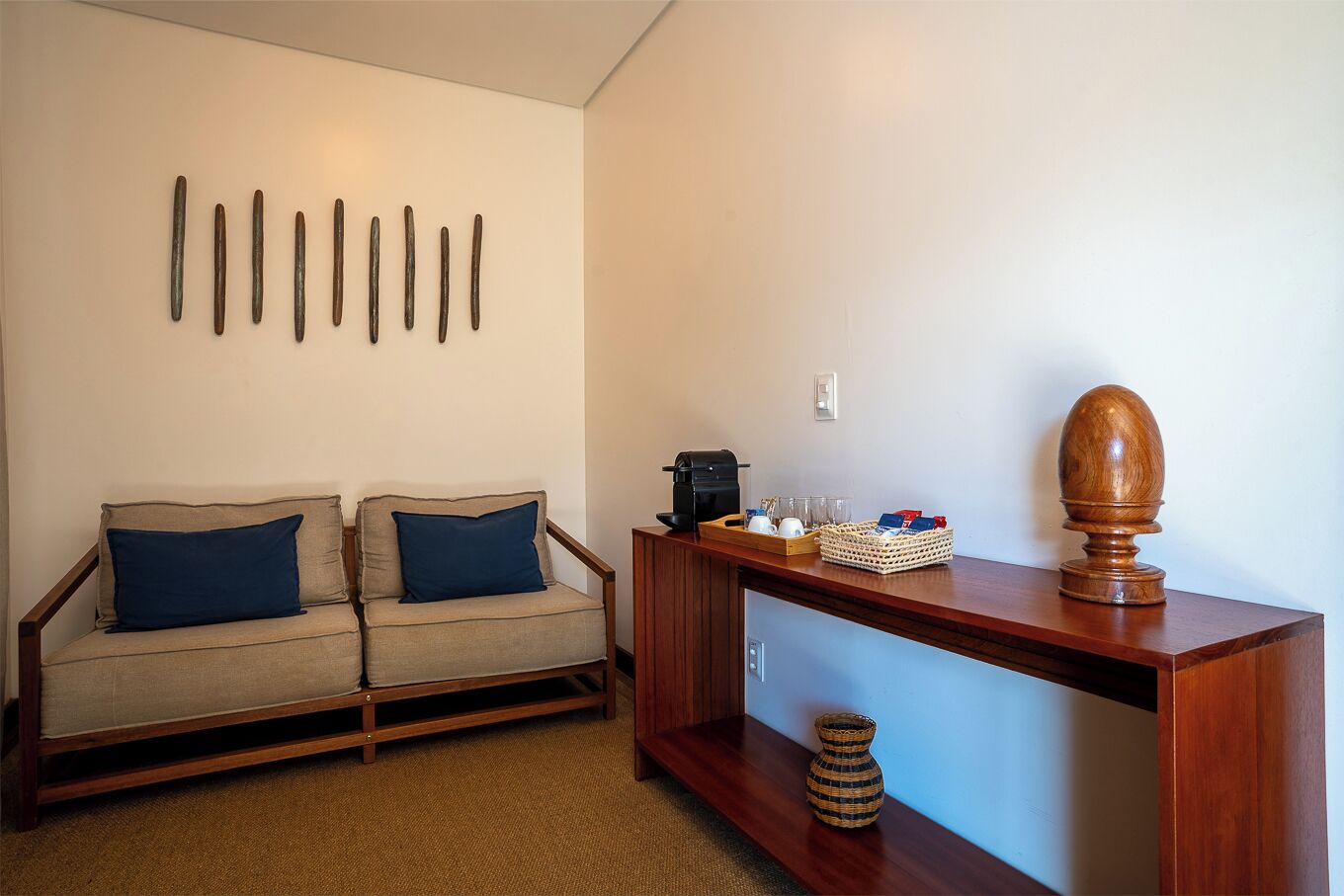 A living room with a sofa, a coffee table, a decorative wooden headpiece, and a wall-mounted light fixture.