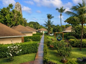 Ein Resort mit mehreren bungalowartigen Gebäuden, einem Holzweg, üppiger Vegetation und Palmen.
