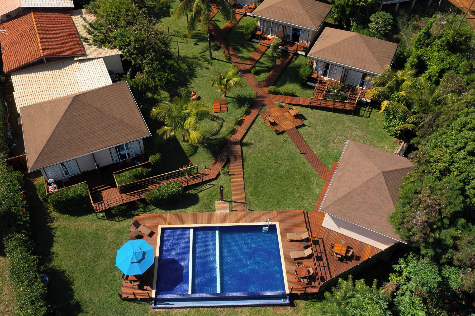 A residential area with a swimming pool, wooden deck, and houses with tiled roofs.