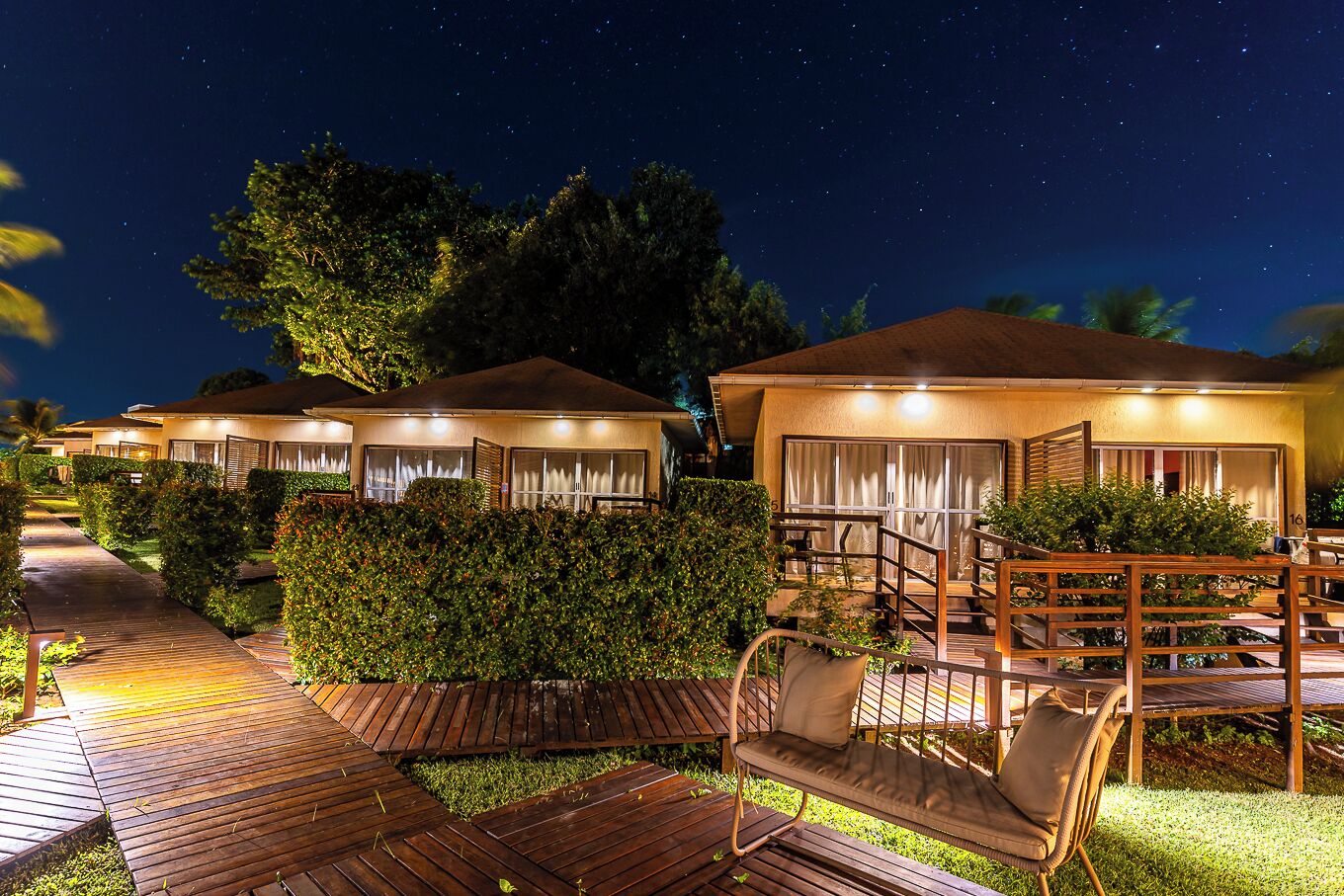 A nighttime view of a resort with multiple overwater bungalows, each featuring a covered patio and a pool area.