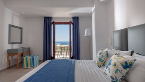 Quarto com cama, mesa de cabeceira, luminária, janela com cortinas e vista para o mar.
