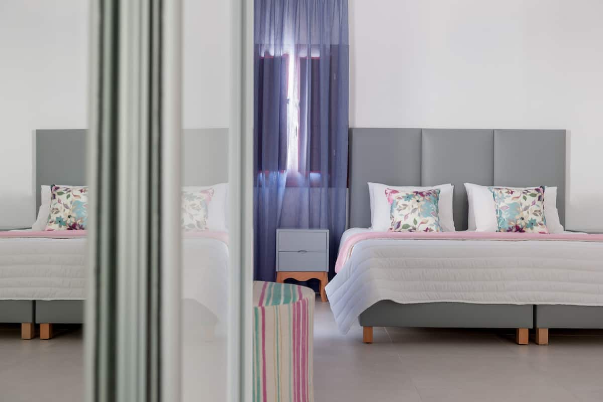 A modern bedroom with two beds, a bedside table, and a small stool.