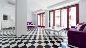 Quarto moderno com piso xadrez, mobiliário branco e janelas grandes com molduras vermelhas.