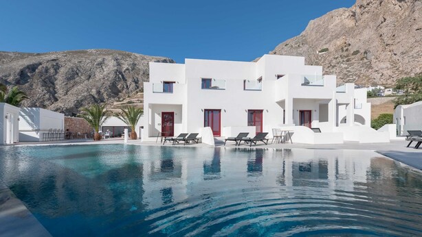 Um edifício moderno e branco com piscina e espreguiçadeiras.