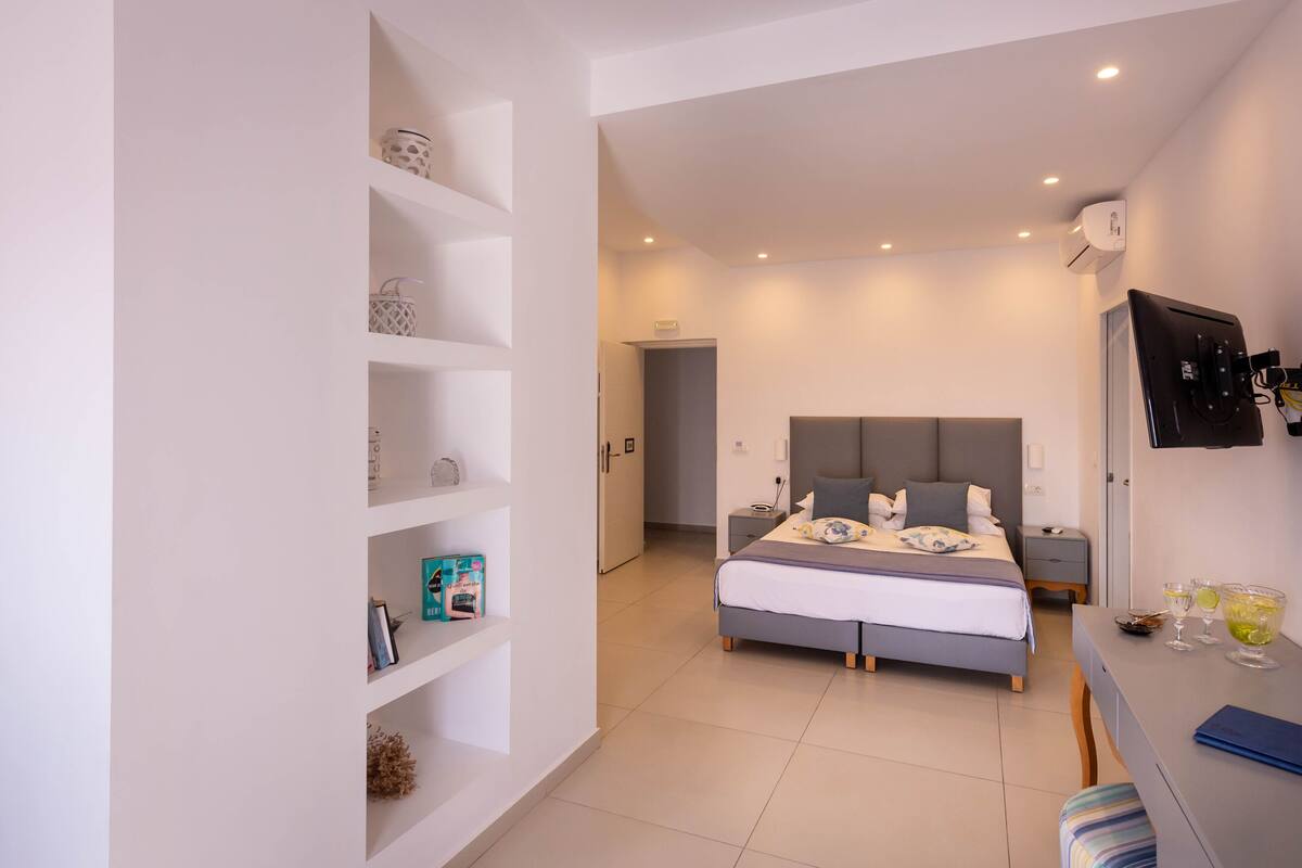 A modern bedroom with a bed, bedside tables, a desk, and a TV.