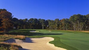 A golf course with sand bunkers, trees, and a clear blue sky. - The Villages at Ocean Edge (Brewster)