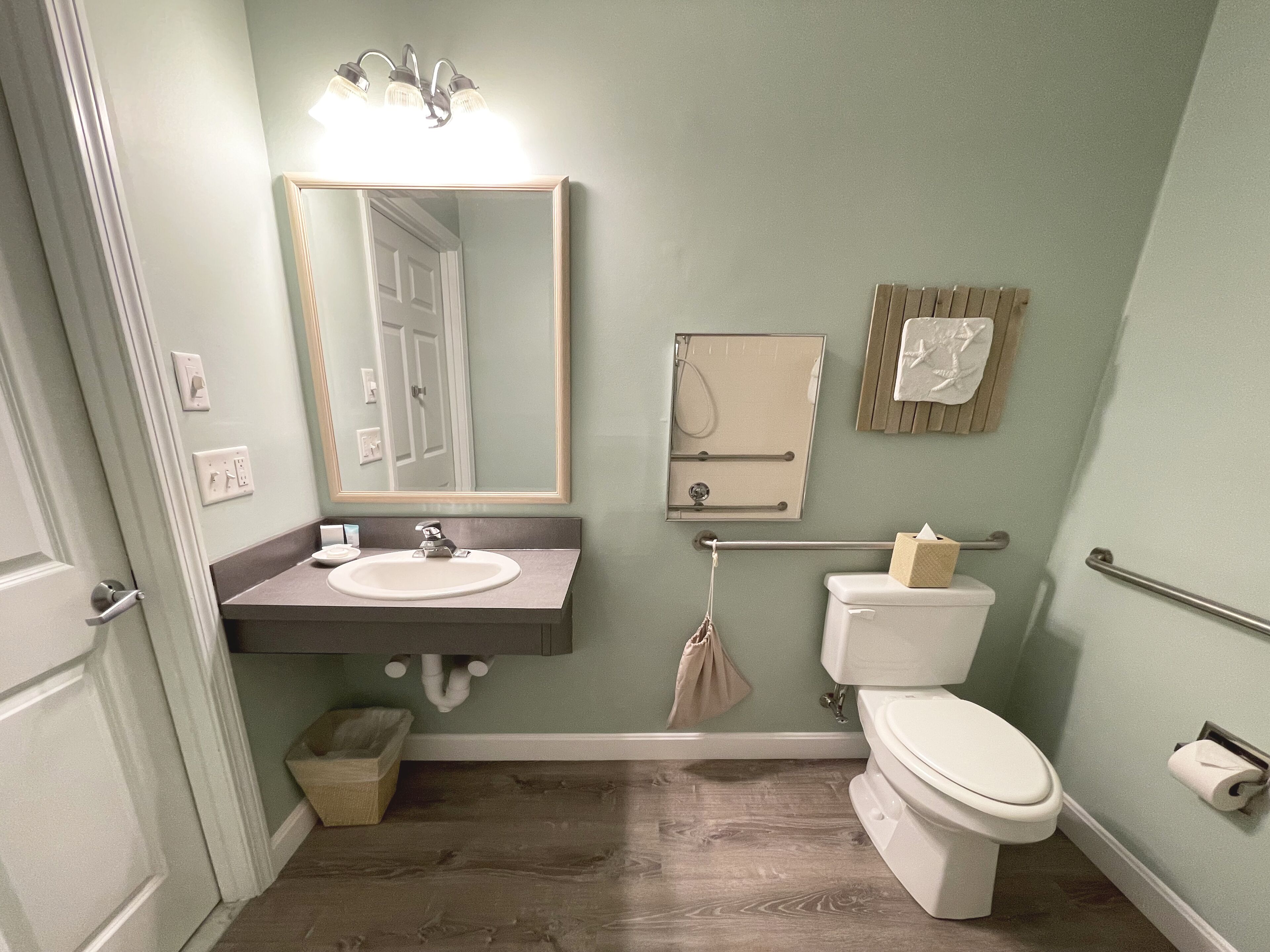 A bathroom with a sink, mirror, toilet, and towel rack.
