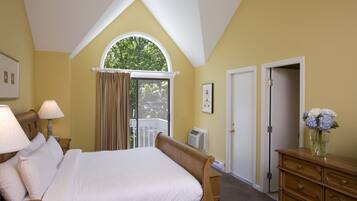 Een slaapkamer met een groot bed, een dressoir, een raam met gordijnen en een deur.