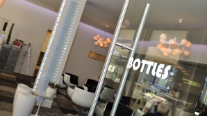 Un interior moderno con una zona de recepción, asientos y un cartel que dice "BOTTIES".