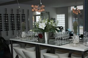 A bar area with a long counter, multiple glasses, and a potted plant.