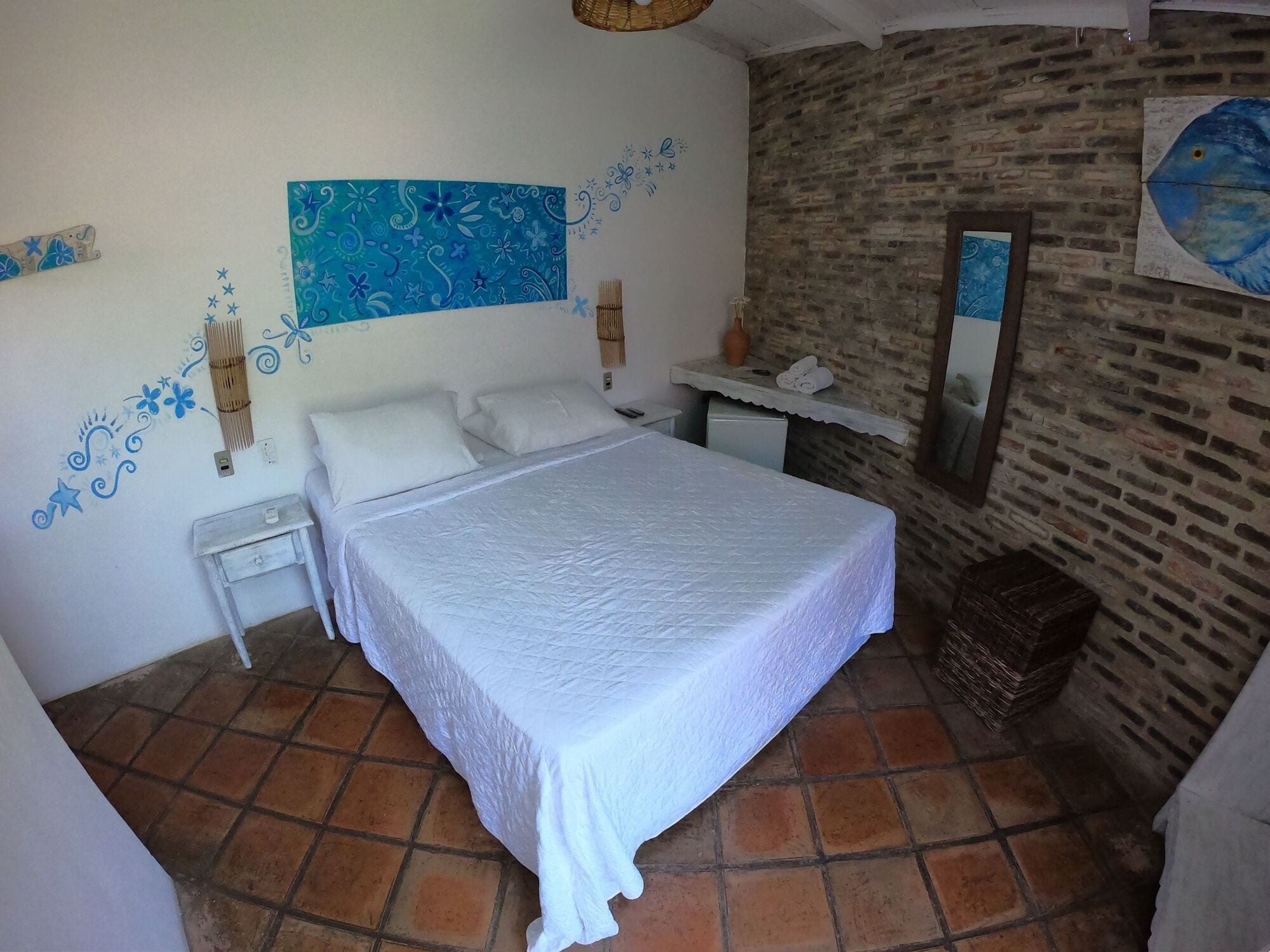 Un dormitorio con cama, mesita de noche, cómoda, espejo y una pared con estampado floral azul.