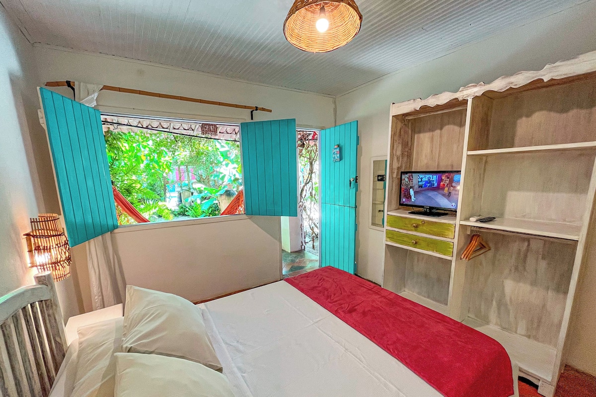 Quarto com uma cama, televisão e guarda-roupa.