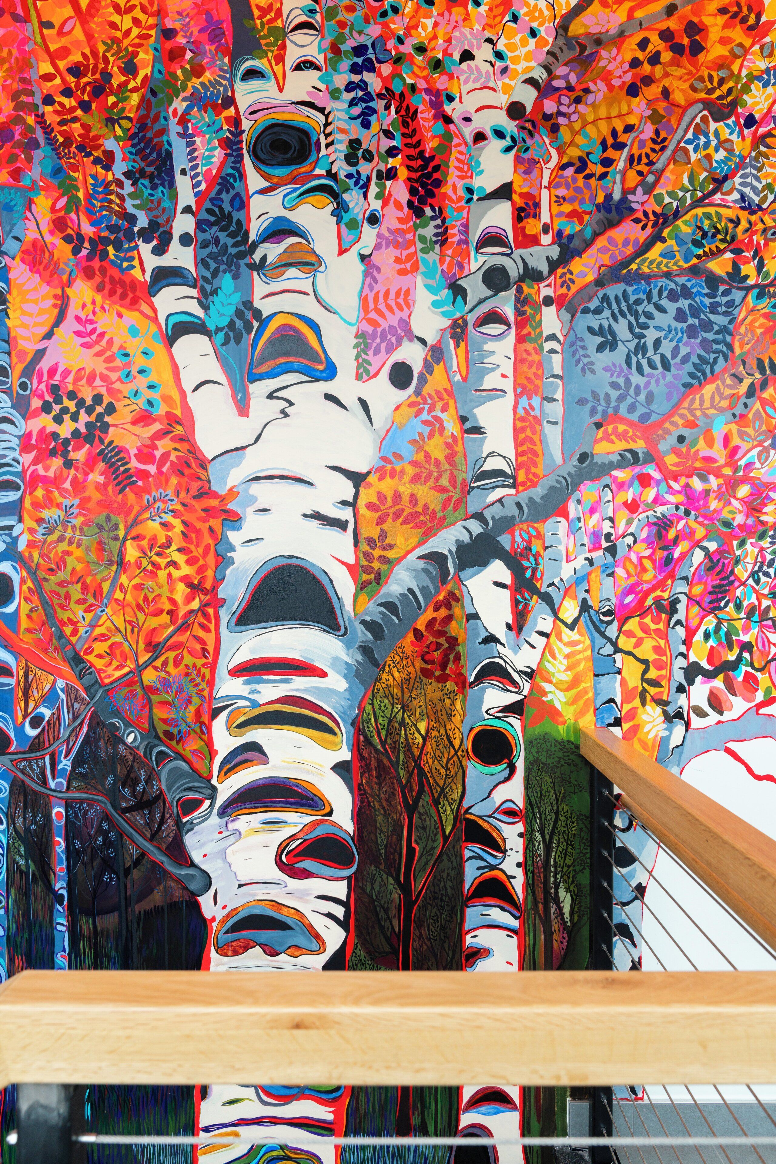 A colorful mural with abstract tree designs and a wooden bench.