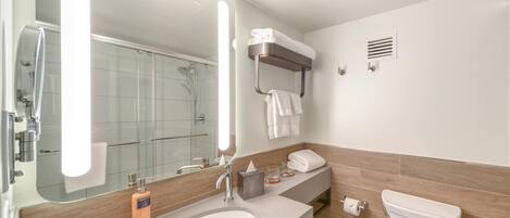 A modern bathroom with a large mirror, a sink, a toilet, and a shower area.