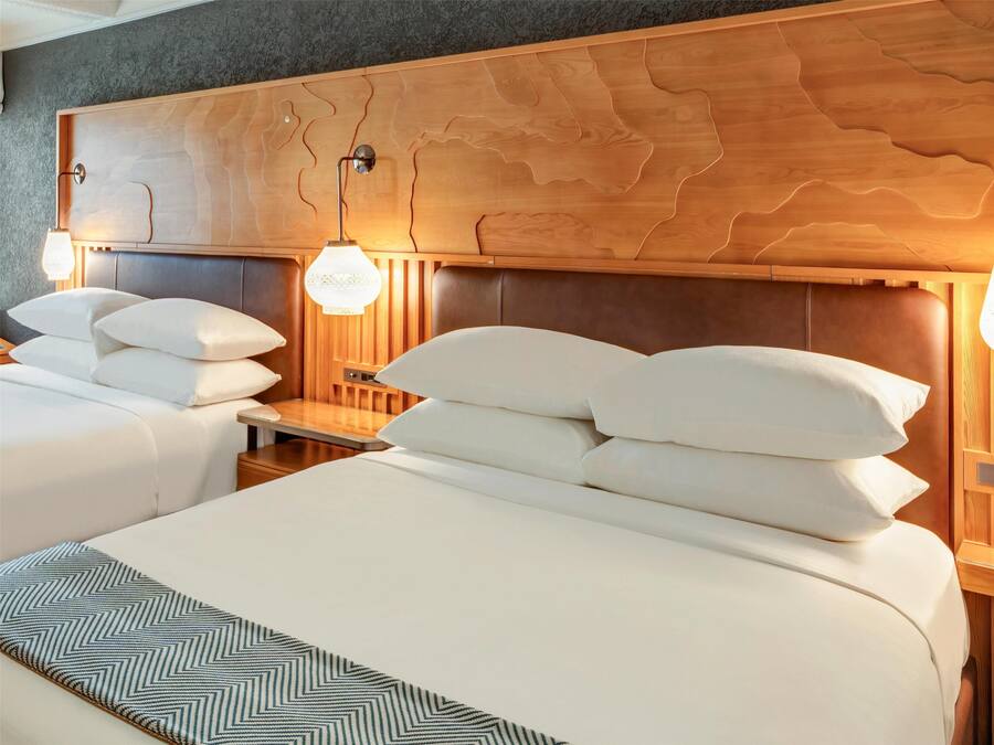 Una habitación de hotel con dos camas, cabeceros de madera y lámparas de noche.